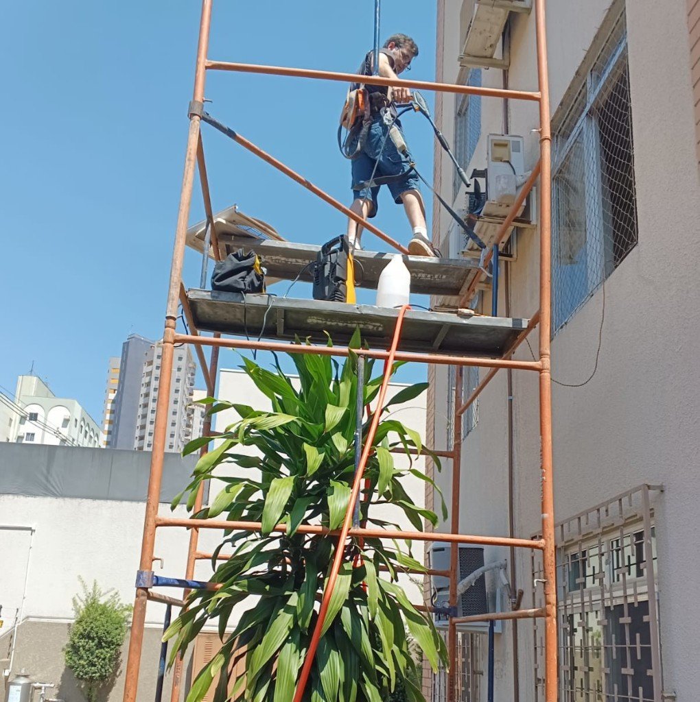 Profissional realizando lavagem externa em altura com segurança